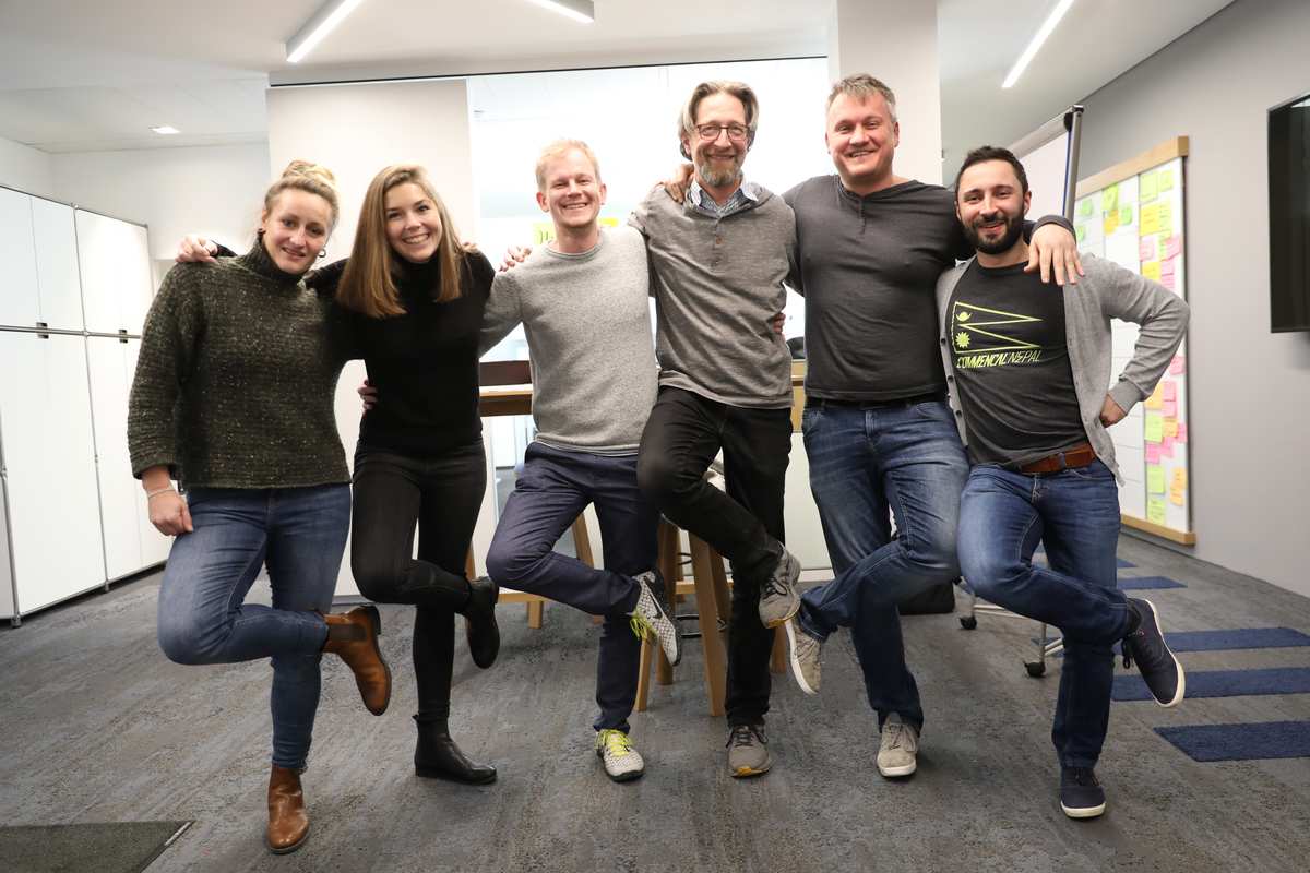 a team of 6 people posing as line dancers in the office